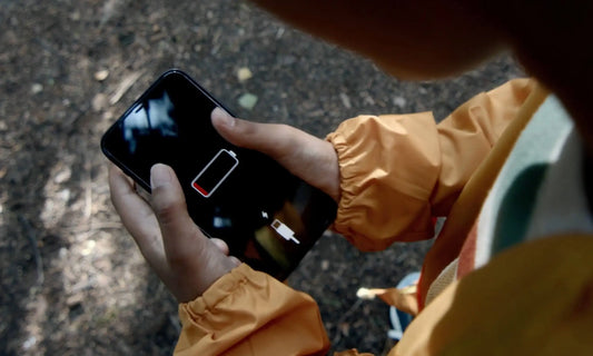 Person holding a phone showing a low battery warning, representing 7 corporate burnout myths and feeling drained at work