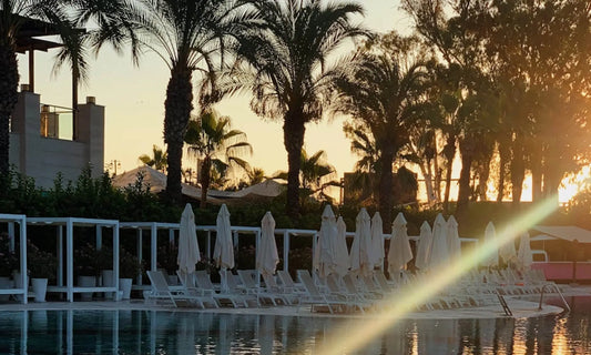Empty sun loungers and closed umbrellas at a resort pool at sunset, illustrating why vacations don't fix burnout