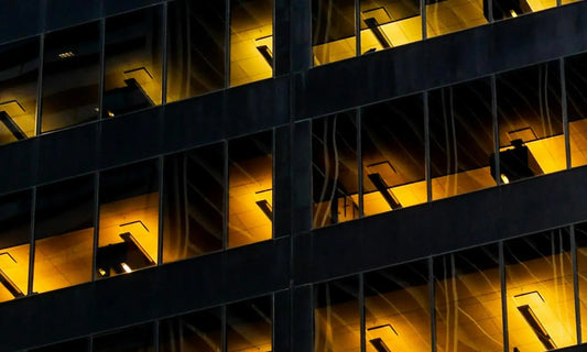 Office building lit up at night with dark structural grid, representing the need to set boundaries at work and protect personal time