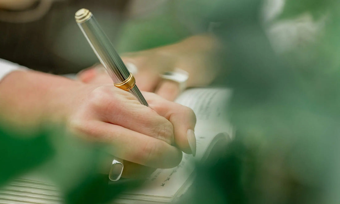 Close-up of a hand writing in a journal with a pen, representing journaling for burnout recovery and resetting the mind daily